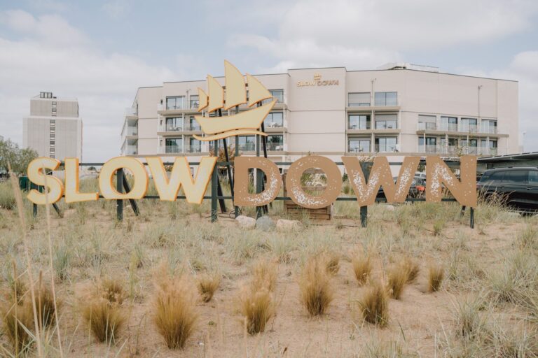 Slow-Down-Schriftzug vor dem Hotel SlowDown Bottsand an der Küste.